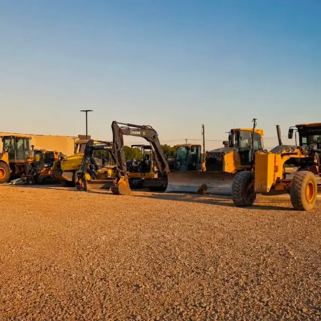 Wilson Contracting excavators, loader and motor grader lined up at sunset