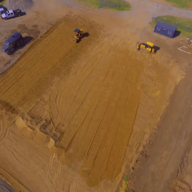 Aerial view of equipment grading a large dirt pad